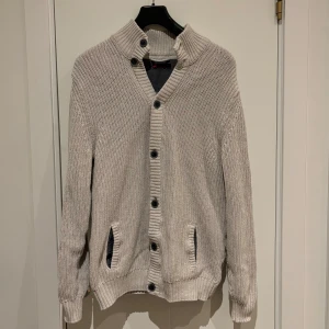 Stickad Kofta - Säljer en snygg beige stickad kofta från Dressmann. Perfekt nu till vintern, inga defekter, bra skick. Köpt i storlek M men sitter som en L. Hör av dig vid frågor eller funderingar:)
