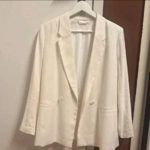 Vit kavaj från H&M🤍 - Elegant vit oversized kavaj från H&M med klassisk design och två knappar framtill. Tillverkad i ett lätt och bekvämt material. Den har storlek S och den är oanvänd 🥰