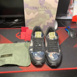 Valentino Garavani rockrunner - Snygga Valentino Garavani sneakers i ett coolt kamouflagemönster. Skorna har snörning och kommer med en praktisk förvaringspåse. Perfekta för att ge din outfit en unik touch.  Ingår dustbag tags och allt förutom kvitto då dom är köpta online. Finns inga detektor på skorna.