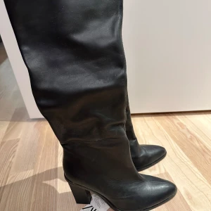Svarta stövlar med klack - Eleganta svarta stövlar i skinn med spetsig tå och klack. De har en praktisk dragkedja på sidan för enkel på- och avtagning. Perfekta för både höst och vinter. Köpta på zara för 1495kr säljs för 800kr  st 36. Säljs pga aldrig använt dom.