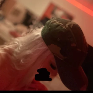 Camouflage keps - Säljer en cool camouflage keps i gröna och bruna nyanser. Perfekt för en avslappnad stil eller utomhusaktiviteter. Kepsen har en klassisk passform och justerbar rem baktill för bästa passform. Passar både till vardags och äventyr!