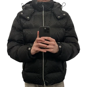 Svart pufferjacka från Boss - Säljer en snygg svart pufferjacka från Boss i mycket bra skick storlek 46=S. Jackan har ett diskret mönster och är perfekt för vintern. Den är långärmad med dragkedja och har en hög krage för extra värme(def finns). Passar perfekt för kalla dagar! Original pris 5,799kr boss egna hemsida 