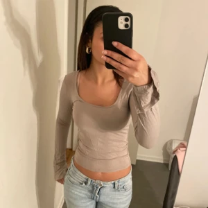 Beige långärmad topp från Gina Tricot - Säljer en snygg beige långärmad topp från Gina Tricot i storlek S. Toppen har en tight passform och är perfekt för både vardag och fest. Den är supermjuk och bekväm att ha på sig. Passar perfekt till jeans eller kjol för en stilren look.
