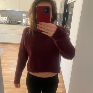 Vinröd  tröja - Mysig vinröd tröja i fluffigt material. Den är croppad och har långa ärmar, perfekt för höst och vinter. Passar bra till både jeans och kjol för en avslappnad look.