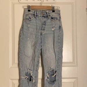 Ljusa jeans med slitningar - Säljer ett par ljusa jeans med hög midja och coola slitningar på knäna. 