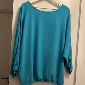 Turkos tröja med trekvartsärm - Säljer en turkos tröja med trekvartsärmar och lös passform. Tröjan har en rund halsringning och elastisk nederkant för en bekväm stil. Perfekt för en avslappnad look.