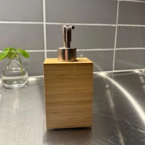 Tvålpump i bambu och metall - Stilren tvålpump med en fyrkantig design i bambu och en metallpump. Perfekt för att ge badrummet en naturlig och modern touch.