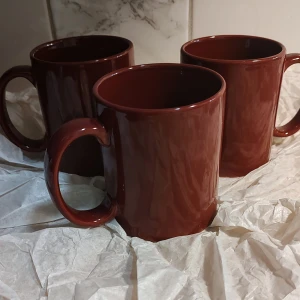 Tre Vinröda muggar med stort handtag - Säljer tre stilrena Vinröda muggar med ett stort handtag som är 8 cm långt. Varje mugg rymmer 4 dl, perfekt för kaffe eller te. Muggarna har en blank yta och en klassisk design som passar i alla kök. Perfekt nu till Jul/Nyår. 3st för 25:- Oanvända med prislappar kvar 