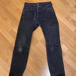 Indigofera gunpowder raw selvedge denim - Snygga svarta jeans från Indigofera med klassisk femficksdesign och knappgylf. Jeansen har en snygg och unik tvätt. Det är raw selvedge denim.