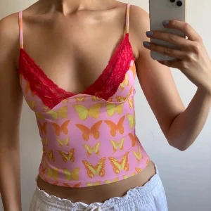 Rosa linnetopp med fjärilsmönster o-mighty  - Säljer denna söt rosa linnetopp med färgglada fjärilar och röda spetsdetaljer. Köpt på plick, i perfekt skick