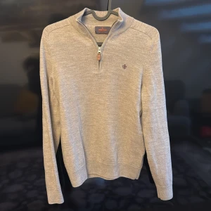 Beige tröja med dragkedja från Morris - Snygg beige tröja från Morris i 100% merinoull. Tröjan har en halv dragkedja och en liten broderad logga på bröstet. Perfekt för kyligare dagar med sin mjuka och bekväma passform.