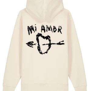 Beige hoodie med tryck - Säljer en supermjuk beige hoodie med ett coolt tryck på ryggen. Texten 'Mi Amor' och ett hjärta med en pil ger den en unik look. Perfekt för mysiga dagar eller som en statement piece i garderoben. Passar både till vardags och chillkvällar.