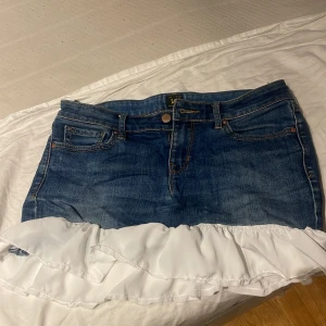 Jeanskjol med volangdetalj  - Säljer en superfin jeanskjol i blå denim med en söt vit volangdetalj längst ner. Perfekt för sommardagar eller en avslappnad fest. Kjolen har en klassisk femficksdesign och en bekväm passform. Den är i mycket bra skick! Den är självsydd med low waist jeans från lee 💘