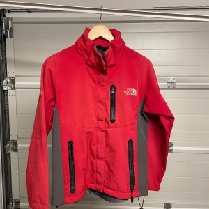 Röd jacka från The North Face - Säljer en röd jacka från The North Face i bra skick. Den har en dragkedja framtill och praktiska fickor med dragkedjor. Perfekt för höst och vinter med sin varma och tåliga design. Jackan har långa ärmar och en hög krage för extra skydd mot kyla. Säljes i befintligt skick. Storlek: M