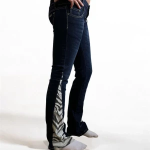 Mörkblå jeans med zebramönster - Coola mörkblå jeans med unika zebramönstrade detaljer längs benen. De har en klassisk femficksdesign och kontrastsömmar som ger en snygg look. Perfekta för dig som vill sticka ut!  Midjemått (mätt platt): 41 cm Grenmått: 17 cm Innerbenslängd: 85 cm  Skriv om kk har fler frågor!😊
