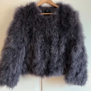 Grå fjäderjacka från WOS - Lyxig fjäderjacka gjord av äkta strutsfjädrar från wos, fin grå/blå färg! Jättefint skick, använd fåtal gånger. Nypris 1499. Pris kan diskuteras. Strl S/M