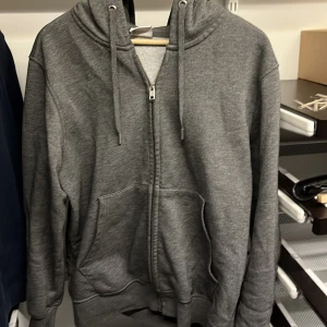 Grå hoodie från Mango - Säljer en grå hoodie från MNG med dragkedja och justerbar huva. Tröjan har fickor framtill och är perfekt för en avslappnad stil. Jävligt bra kvalitet väldigt lite nopprig syns knappt. Size S