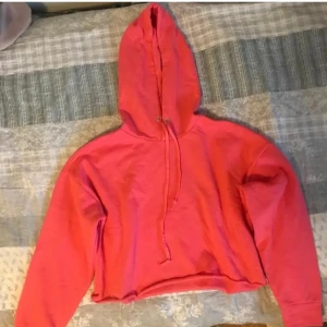 Rosa croppad hoodie - Säljer en snygg neon rosa croppad hoodie med huva och dragsko. Perfekt för en avslappnad stil. Passar bra till jeans eller leggings. 