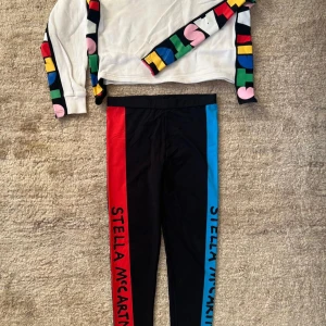 SNYGGT STELLA MCCARTNEY KIDS SET I MYCKET GOTT SKICK - STELLA MCCARTNEY KIDS  SPORT LEGGINGS GIRL LEGGINGS - NAVY  Snygga mörkblåa leggings av Stella McCartney Kids. De är gjorda av återvunnen polyamid och har färgglada penngrafik längs sidorna av varje ben och en bekväm resår i midjan. Mjuk och stretchig jersey. 78% återvunnen nylon, 22% elastan. Storlek 14y, vilket motsvarar 164. + STELLA MCCARTNEY KIDSWHITE ORGANIC COTTON Sweatshirt i vitt med färgglad logga runt ärmar och vid sidorna.  Ny pris för hela setet: 1900 kronor Mitt pris 500 kronor!