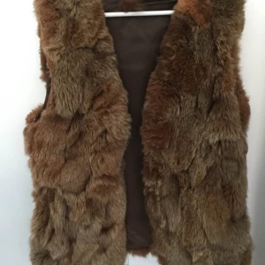 Brun pälsväst - Säljer en snygg brun pälsväst med mjukt foder. Perfekt för att hålla sig varm och stilren under kyligare dagar. Västen har en naturlig look och är lätt att matcha med olika outfits.                                                                               Äkta pälsväst passar Smalla medium Large,one size