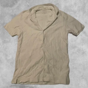 Vit kortärmad skjorta från Lindbergh - Säljer en stilren vit kortärmad skjorta från Lindbergh i slim fit. Perfekt för en avslappnad men ändå uppklädd look. Skjortan har knappar framtill och är tillverkad i ett mjukt material.