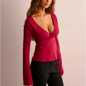 Röd långärmad topp med djup urringning - Snygg röd topp med djup v-ringning och långa ärmar. Toppen har en öppen rygg med en dekorativ rosett. Perfekt för en stilfull look. Säljer pga den är för stor, men den är i nyskick ❤️❤️❤️nypris är 299kr, mitt pris är 150🥰🫶🏽