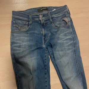 Blå jeans från Replay - Snygga blå jeans från Replay i modellen Anbass. De hare en klassisk femficksdesign med dragkedja och knapp. Perfekta för en avslappnad stil med en modern touch. Säljer för att de är försmå