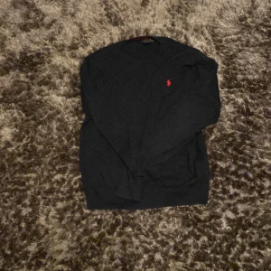Svart tröja från Ralph Lauren - Säljer en stilren svart tröja från Ralph Lauren i bomull. Tröjan har en liten röd logotyp på bröstet och långa ärmar. Perfekt för en klassisk och avslappnad look. Skick 8/10 inga skador, pris 400 storlek är Xs och 160 cm hör av vid minsta fråga!