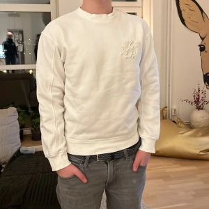Vit sweatshirt från H&M - Säljer en stilren vit sweatshirt från H&M med broderad logotyp på bröstet. Tröjan har en loose fit och långa ärmar, perfekt för en avslappnad look. Passar bra till jeans eller chinos.