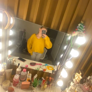 Gul stickad tröja - Säljer en härlig gul stickad tröja med v-ringning. Tröjan har en lös passform och långa ärmar, perfekt för kyligare dagar. Den ribbade strukturen ger en fin detalj och extra komfort.