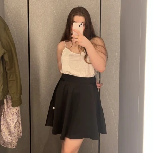 Svart kjol från Armani Exchange - Snygg svart kjol från Armani Exchange med en klassisk A-linjeform. Kjolen har en enkel design som gör den lätt att matcha med olika toppar. Perfekt för en stilren look. Använd fåtal gånger, väldigt bra skick.