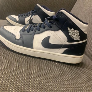 Nike Air Jordans i blått och vitt - Säljer ett par snygga Nike Air Jordans i blått och vitt. Skorna har en klassisk design med snörning och den ikoniska Air Jordan-loggan på sidan. Perfekta för både vardag och fest!
