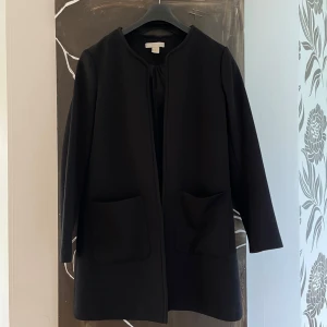 Kappa  - Svart kappa från hm, utan krage som man kan se på bilden. Väldigt stilren med två fickor där fram. Extremt skön 