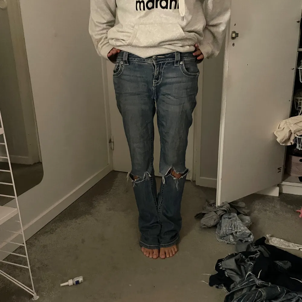 MISS ME blå jeans med coola slitningar på knäna. låg midja och en bootcut passform. Jeansen har snygga detaljer med knappar och fickor bak.midje mått ca : 40 men strechiga. innerbenslängd: ca 79. igensytt hål vid skrevet som inte syns alls. Jeans & Byxor.