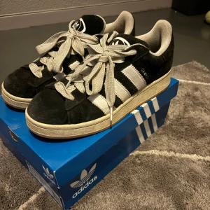 Svarta Adidas Campus sneakers - INTRESSEKOLL⚠️⚠️Skorna har klassiska tre ränder på sidan och en bekväm gummisula. De är i bra skick och kommer i originalkartong. Perfekta för vardagsbruk!
