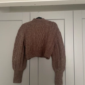 Stickad tröja  - Tröjan är använd ett fler tal gånger. Men fortfarande i fint skick. Själv skulle jag inte säga att den är en magtröja men den är kortare ner till.