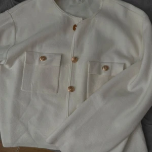 Vit kofta med guld detaljer. - Fin stickad kofta med guld knappar och fickor. Säljer pga att den inte används, använt 1 gång. Kommer att tvättas innan den skickas. 🩷🩷Köpte för 400.