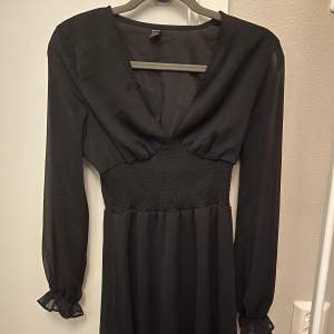 En fin svart klänning som är v-ringad och volang längs ner. Den är använd 1 gång. 