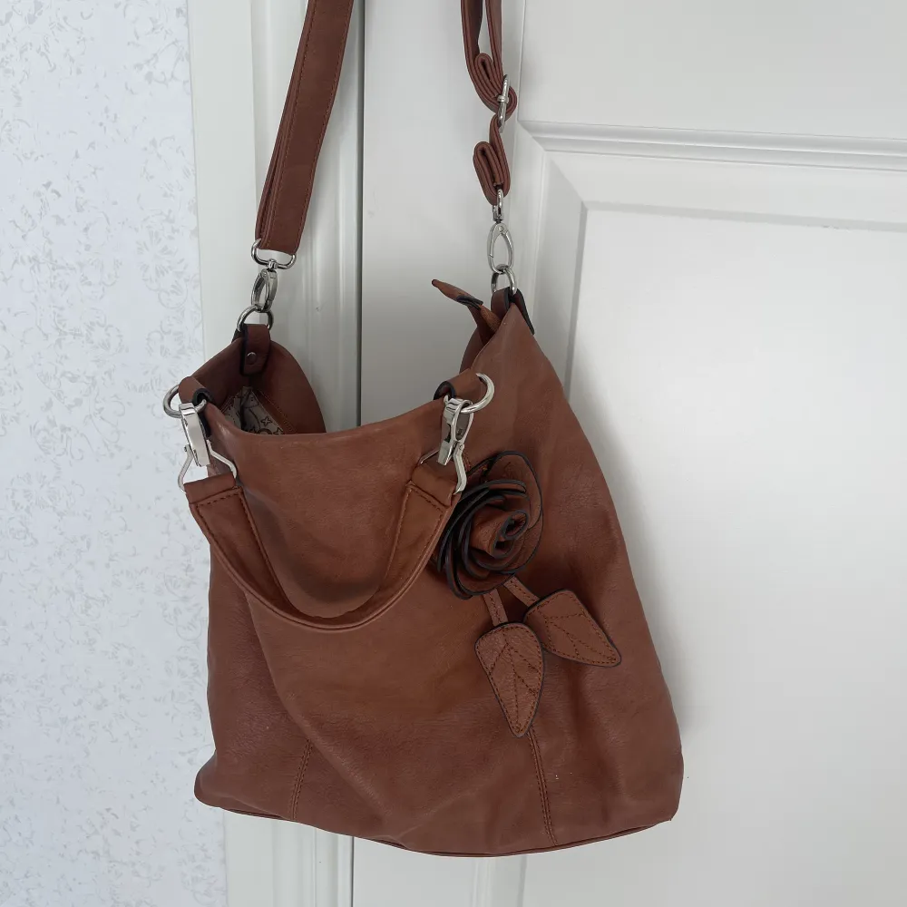 Säljer en fin vintage brun väska med en blom detalj. Märket är okänt.💞. Väskor.