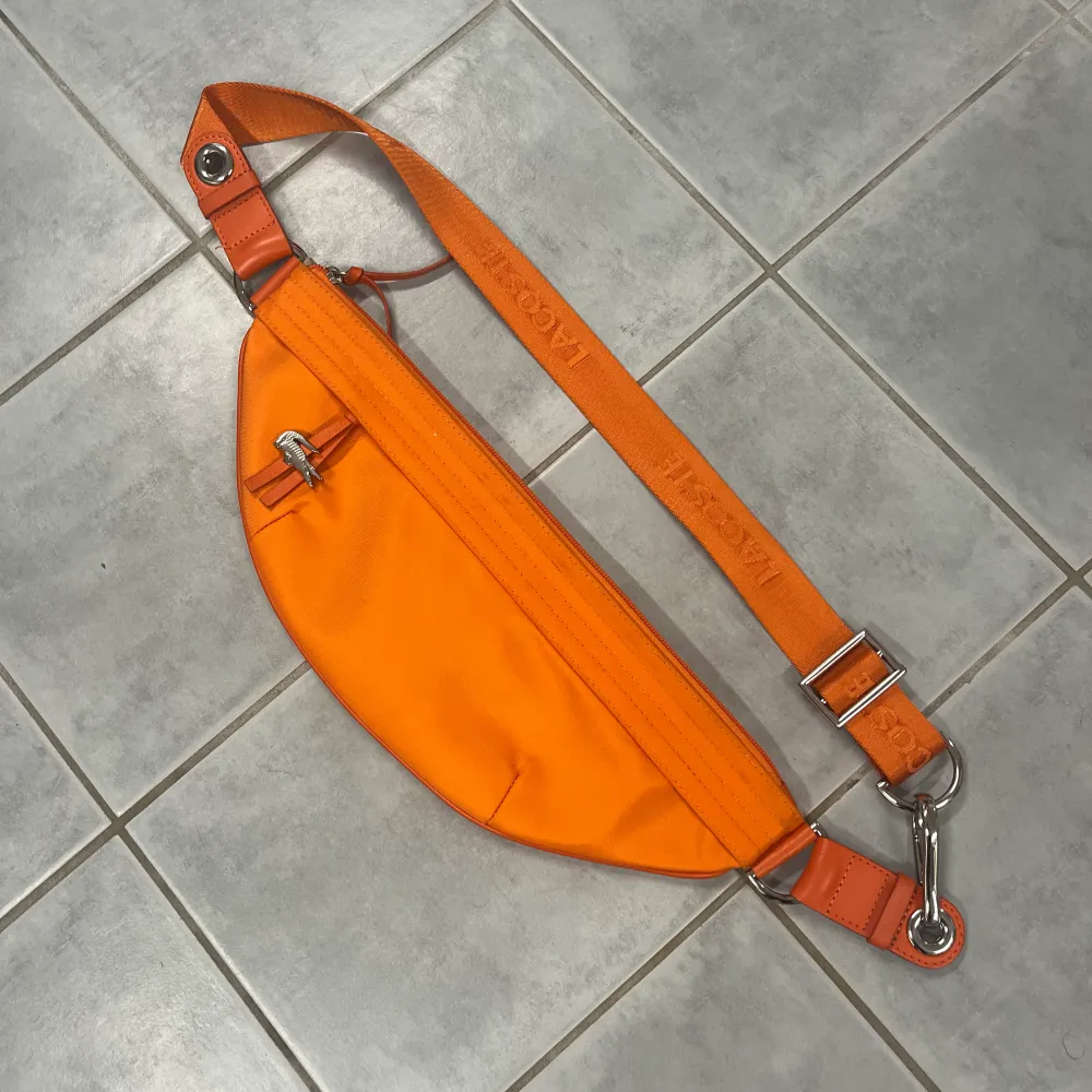 Orange väska från Lacoste i nyskick, ingenting att anmärka på. Accessoarer.