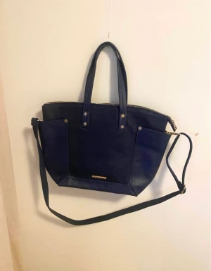 Björn Borg väska - Säljer en handväska från Björn Borg. Den är köpt på outlet här i Sverige för några år sedan. Mörk blå i färgen. Knappt använd då jag endast använder samma väska varje dag.  Mått: Längd: 40 cm  Höjd: 28 cm