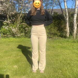 Beige kostymbyxor - Kostymbyxor i beige från Misslisibells kollektion med NAKD, knappdetaljer i midjan, två fickor, två fake-fickor i bak, säljer pga stora till mig