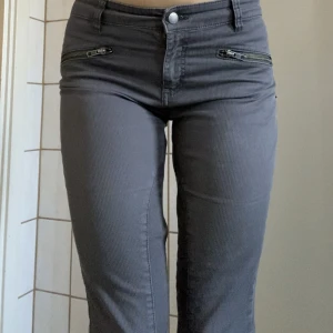 Gråa byxor - Gråa byxor med dragkedjsdetaljer. Storlek: 38. 