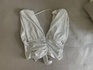 Silvrig topp från Gina Tricot strl XXS oanvänt  - Aldrig använt denna. Passar en XS och liten S skulle jag säga. 