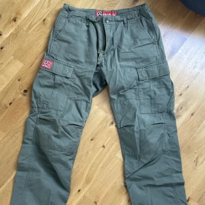 Gröna cargo byxor - Ett par gröna Cargo byxor från molecule. Iprincip i helt nyskick och helt utan defekter. Har band i midjan så den kan justeras så att man har altifrån storlek xs-m!