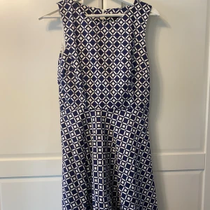 Marinblå klänning.  - Marinblå klänning med mönster från Stockh lm. Insydd i midjan och dragkedja i ryggen. Storlek 36. 