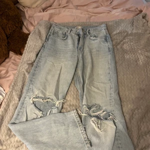 Högmidjade jeans - Ett par jättefina jeans med slitningar på knäna. Använd ett antal gånger men fortfarande i fint skick. Ena hålet har blivit lite uppdraget och därav priset. Men allmänt fina.