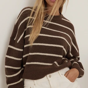 Brun/ beige randig tröja - Stickad tröja i handuksmaterial som  är brun med beiga ränder. Tröjan är lite kortare i modellen men inte croppad riktigt. Är från NA-KD och är i storlek XS. Knappt använd endas få gånger. 