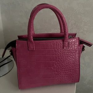 Rosa D väska - Säljer denna skitsnygga handväska som är köpt för ett tag sedan, jättemycket utrymme, band tillkommer, ser helt orörd ut💛