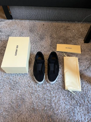 Axel arigato - Säljer ett par Axel arigato 360 laceless i skick 8/10. Mitt pris är 700kr och allt og finns även digitalt kvitto (nypris 2550kr). Skorna är i storlek 43, lite dammiga men går självklart att fixa! Sen har även skorna håll på undersidan men som inte syns.